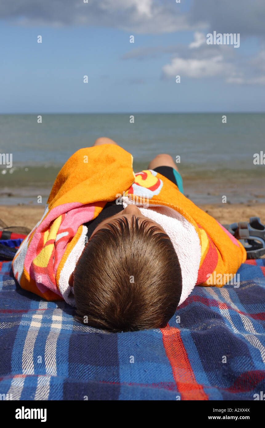 Il mantenimento del calore sulla spiaggia ragazzo giovane di età compresa tra 10 anni avvolti in teli mare spiaggia in Galles Foto Stock