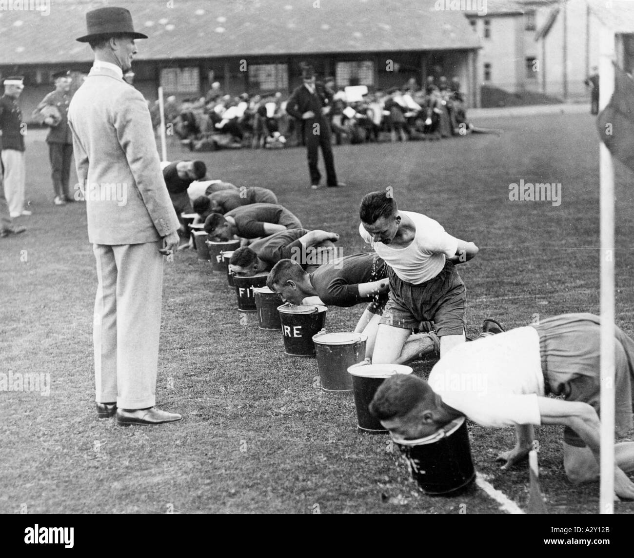 Il 21 luglio 1932, mentre tutti gli occhi erano puntati su Los Angeles, dove dovevano svolgersi i Giochi olimpici luogo il mese successivo questi inglesi stavano praticando i loro sport particolari come la corsa delle mele e dei secchi le loro caserme reggimentali a Caterham i soldati stanno tentando di usare i denti da soli per rimuovere le mele dai secchi del fuoco preso in prestito per lo scopo Waehrend die Weltoeffentlichkeit bereits den im August stattfindenden Olympischen Sommerspielen a Los Angeles entgegengefiebert pflegen diese Englaender AM 21 Juli 1932 ihre ureigenen Sportarten wie das Apfel und Eimer Rennen IM Foto Stock