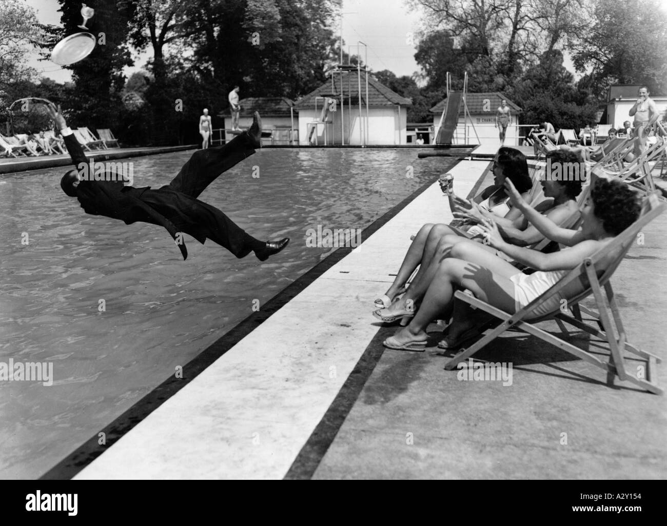 In primavera e in estate, affamati dal sole, le persone uscivano dalle loro case e i fotografi della stampa potevano respirare di nuovo c'era sempre qualcosa di nuovo, anche se era solo un cameriere che cadde in acqua mentre serviva fresco drink in una giornata molto calda a bordo piscina nella città inglese di Watford Im Fruehling und Sommer Stroemen Die Menschen sonnenhungrig aus ihren Wohnungen und die Pressefotografen koennen endlich aufatmen es passiert wieder jeden Tag etwas in der Region und sei es dass an einem sehr heissen Tag im englischen Watford der Oberkellner beim Servieren der kuehlen drink poll Foto Stock