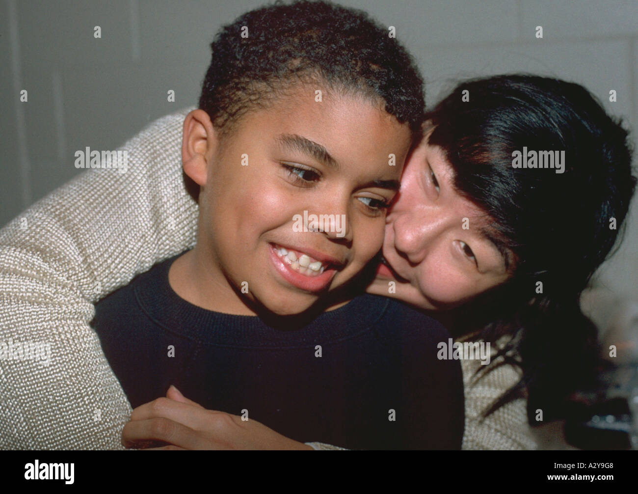 Asiatica leader americani abbracciando ragazzo di 27 anni e 8 nella comunità il gruppo giovanile. St Paul Minnesota USA Foto Stock