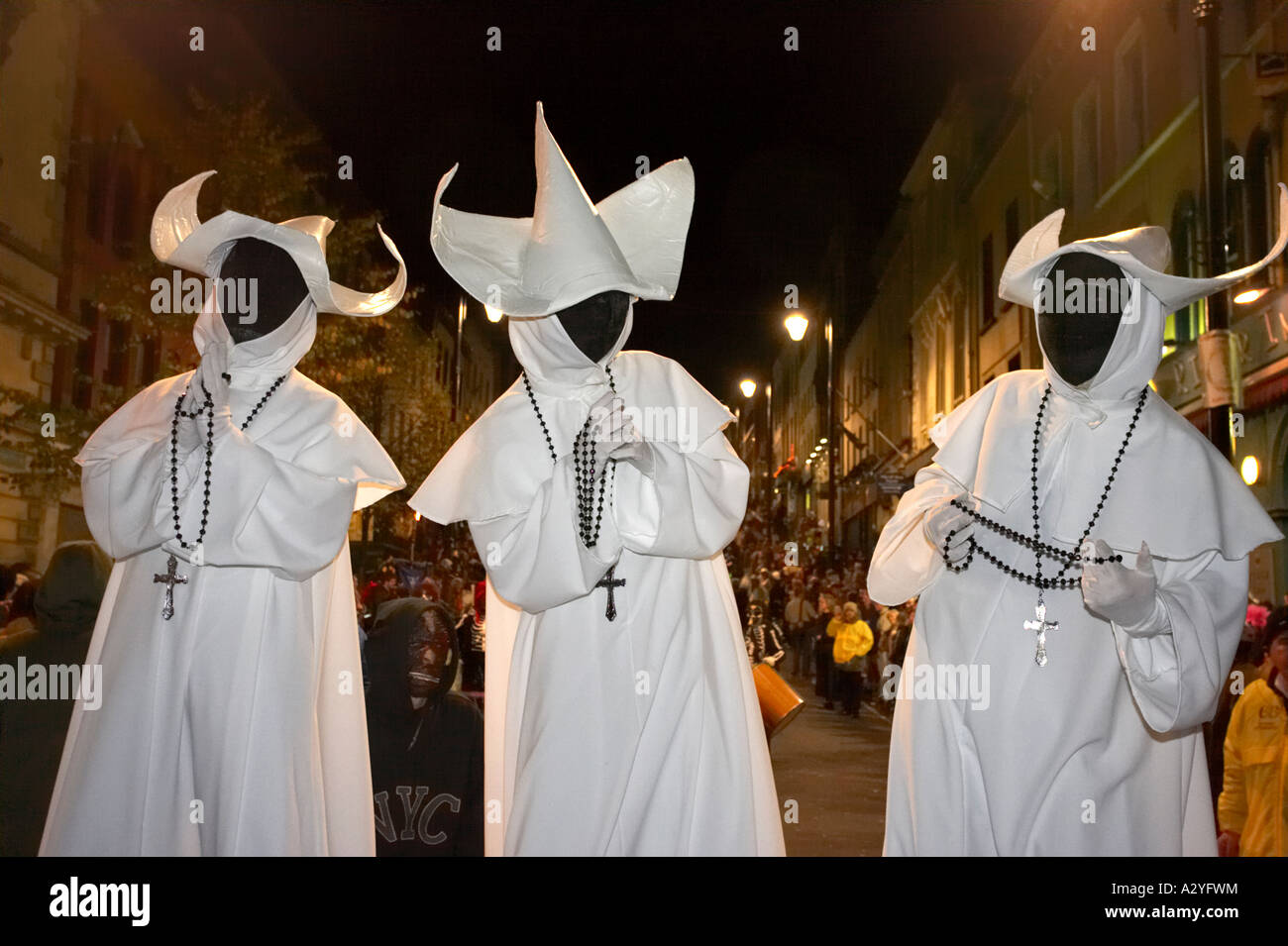 Tre uomini vestiti come i fantasmi di monache con facce di colore nero e i grani del rosario e attraversa pregando Halloween Derry Irlanda Foto Stock