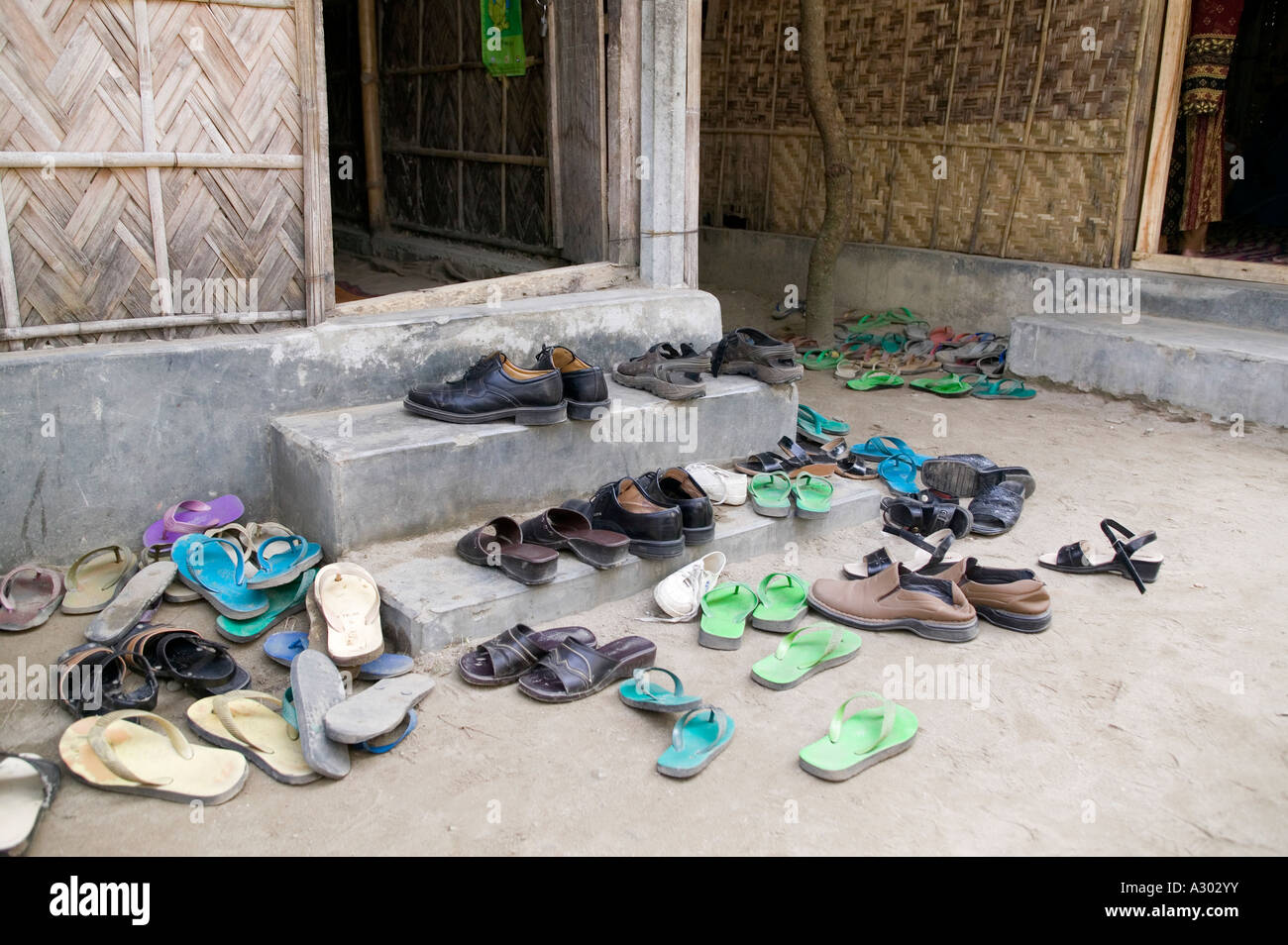Scarpe e flip flop al di fuori dell'entrata di una camera di scuola nel nord del Bangladesh Foto Stock
