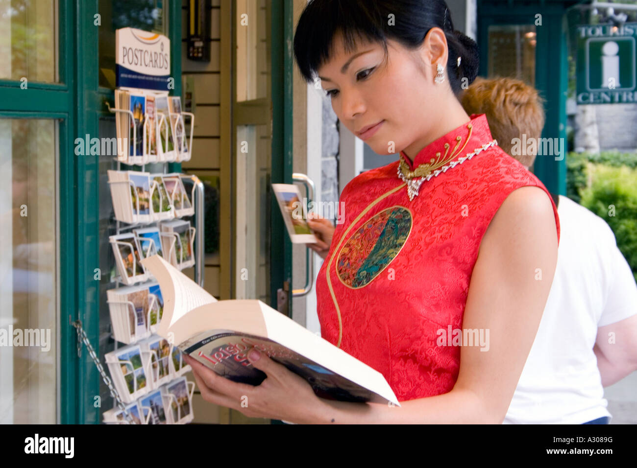 Donna cinese in abito tradizionale scegliendo libro Foto Stock