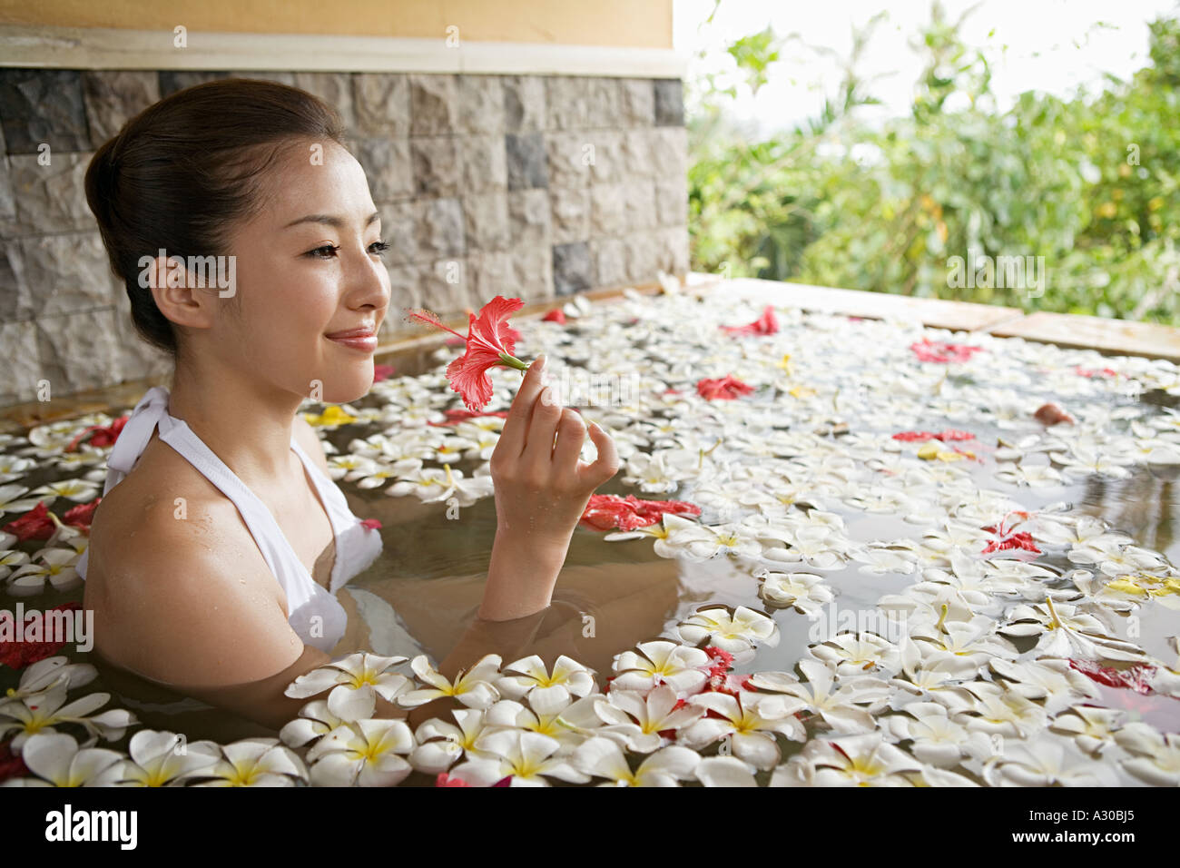 Donna in piscina con petali di fiori Foto Stock