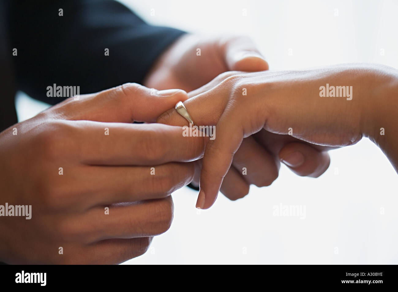 Lo sposo posizionando l'anello nuziale sul dito spose Foto Stock