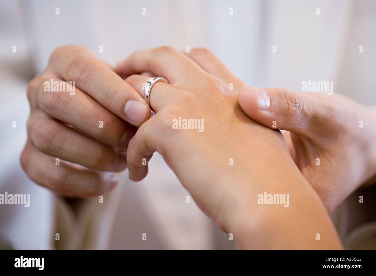 Lo sposo posizionando l'anello nuziale sul dito spose Foto Stock