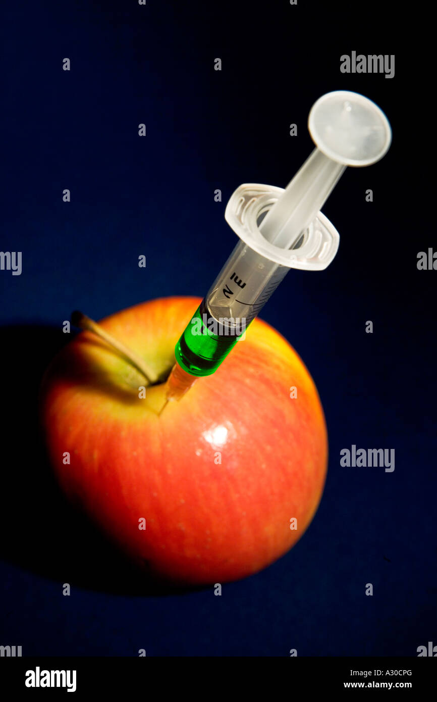 Apple iniettato con liquido verde concetto per rappresentare gli alimenti geneticamente modificati Foto Stock