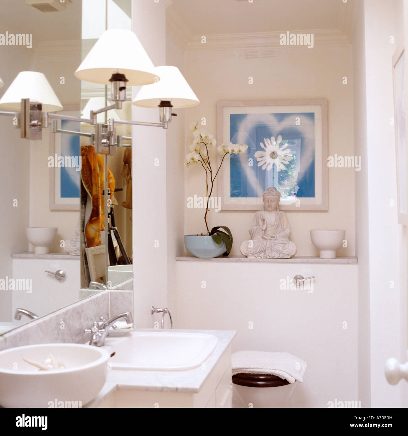 Lampade a specchio nel dipinto di bianco di bagno con statua del Buddha e lavabo Foto Stock