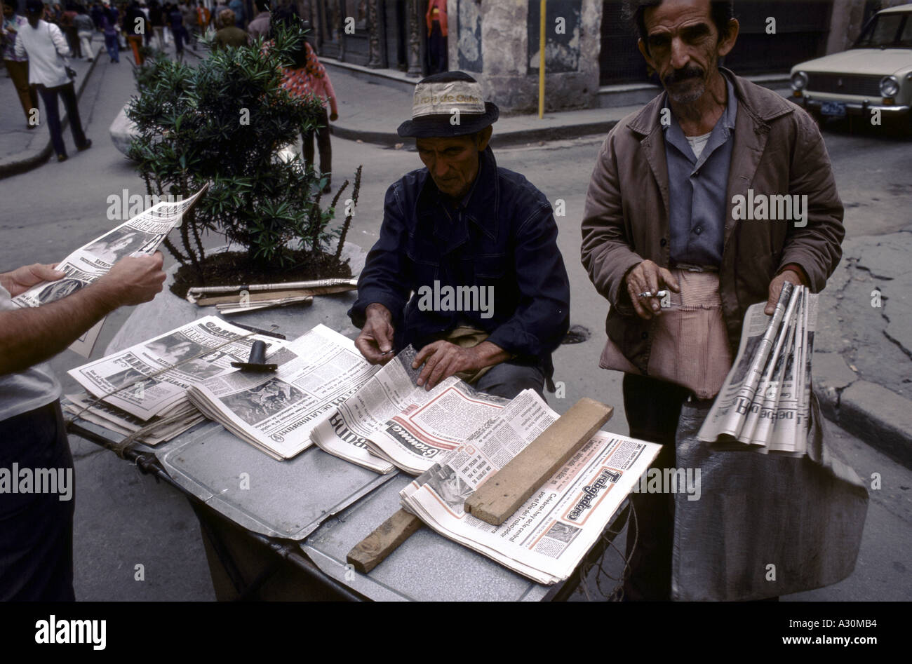 Due uomini anziani vendita di quotidiani su un piccolo box in strada a l'Avana, Cuba Foto Stock