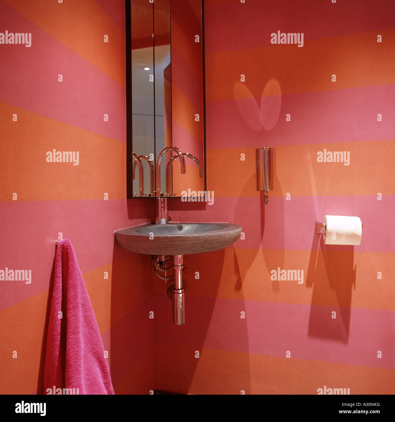 Rosa e arancio listati bagno con lavandino e specchio Foto Stock