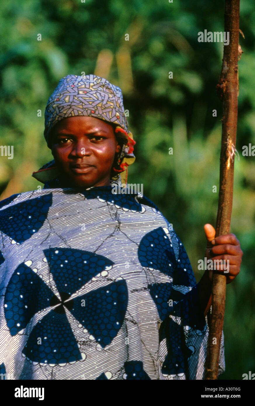 Una donna nigeriana passeggiate con un palo di legno lungo un sentiero rurale tra Accra e Tema Ghana, Africa occidentale. Foto Stock