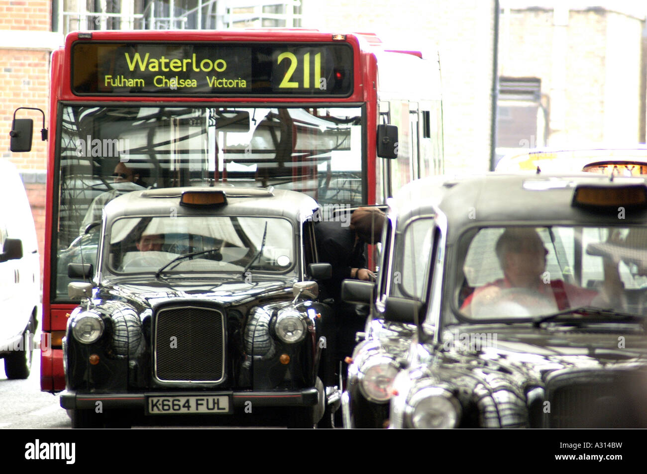 Fotografia di London bus rosso e nero con taxi che mostra alternativa alla guida nella zona di congestione usando trasporti di Londra Foto Stock