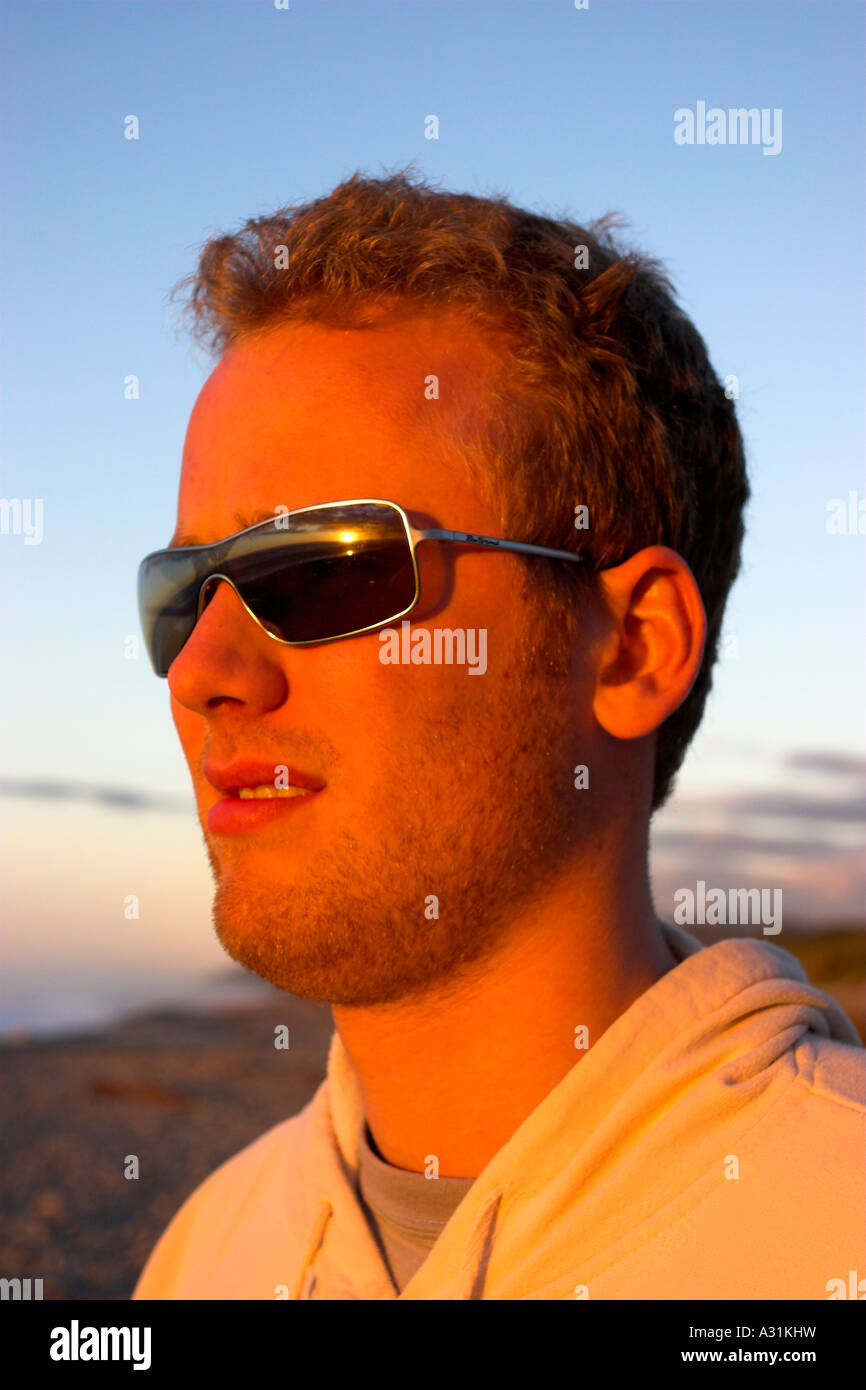 Giovane maschio a guardare il tramonto sul lontano orizzonte. Foto Stock