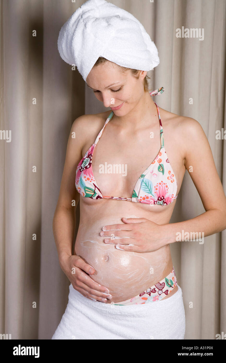 Donna incinta sfregamento idratante nel suo ventre Foto Stock