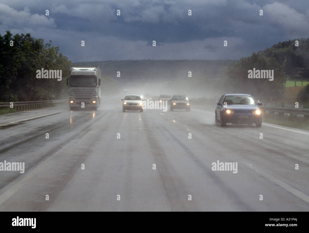 Semi di camion e automobili che viaggiano in autostrada sotto la pioggia Foto Stock