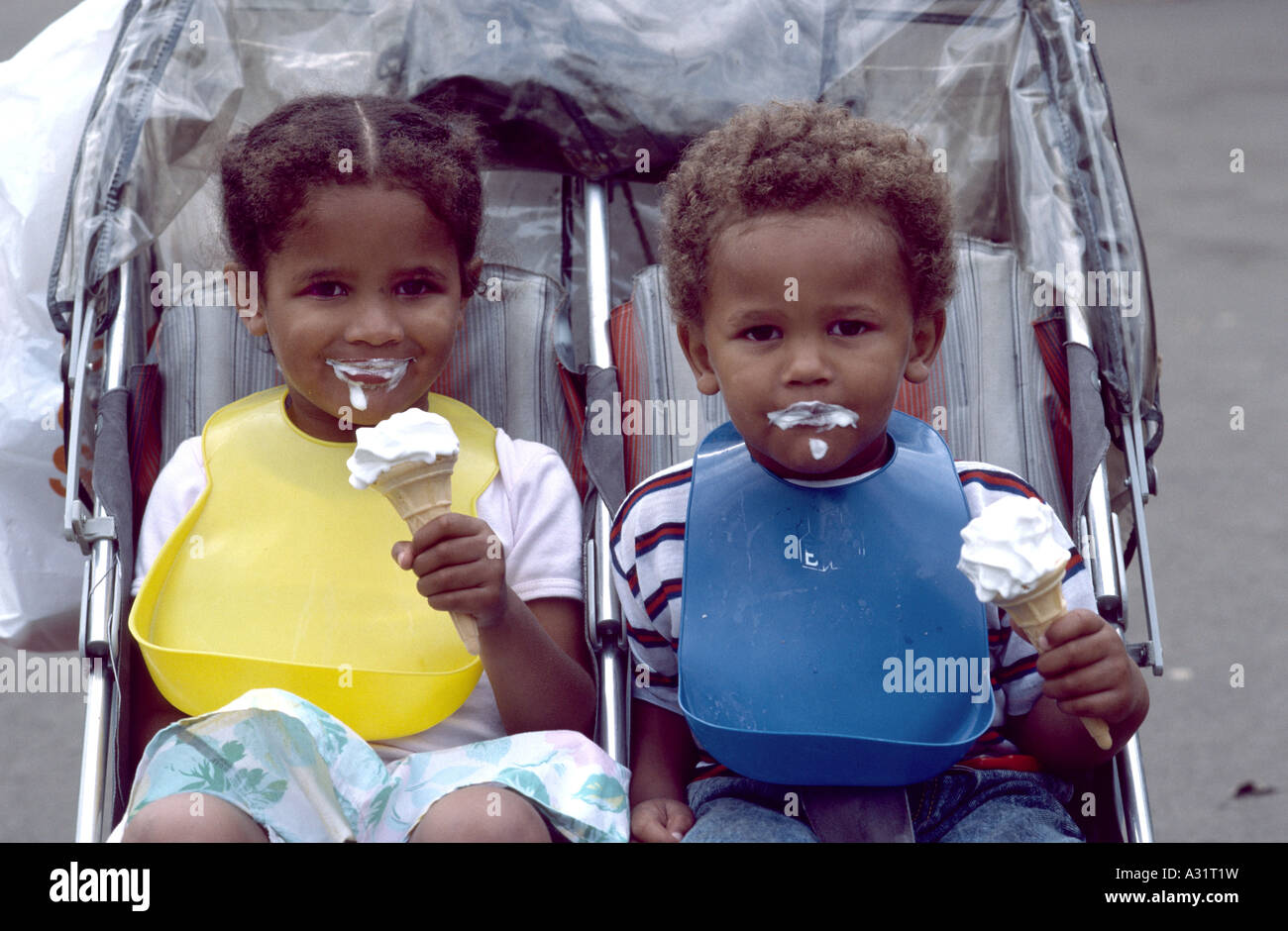Due bambini mangiare gelato seduto in una sedia push Foto Stock