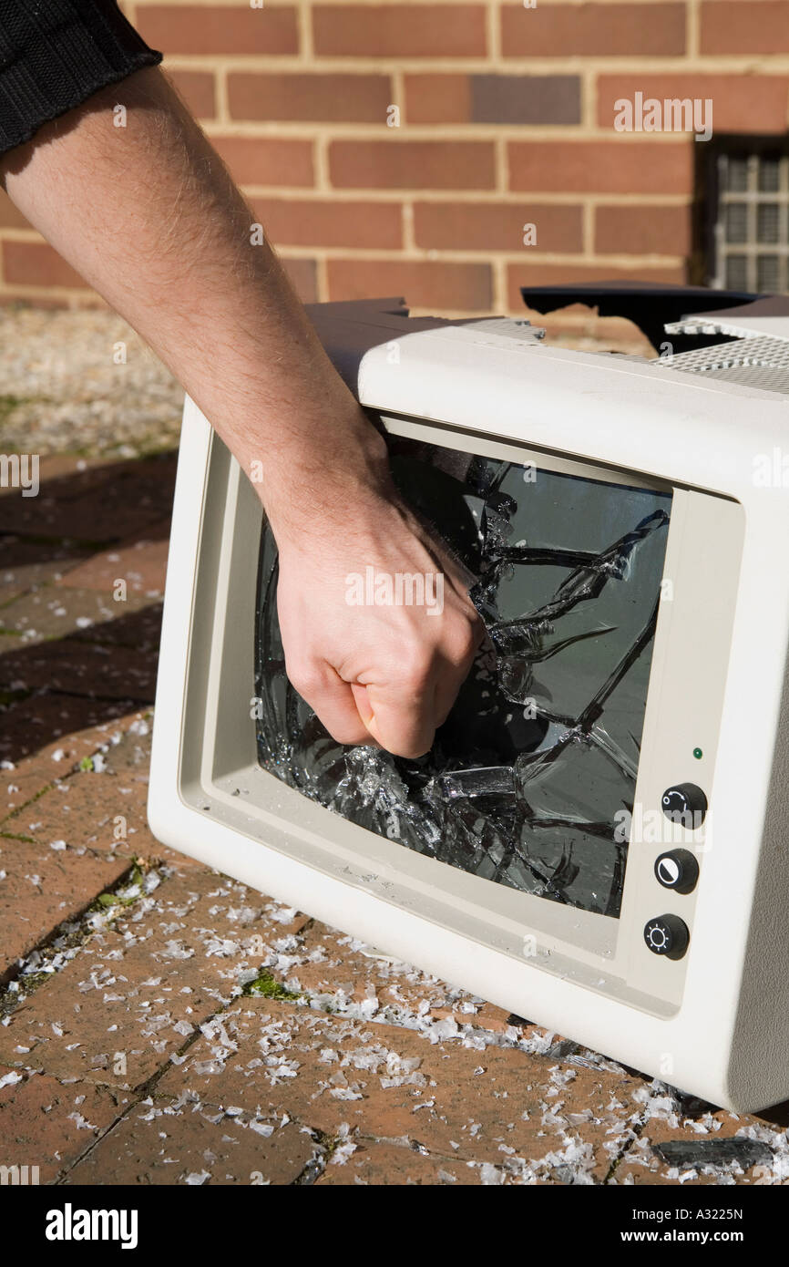 Uomo con il suo pugno per una televisione fracassato Foto Stock