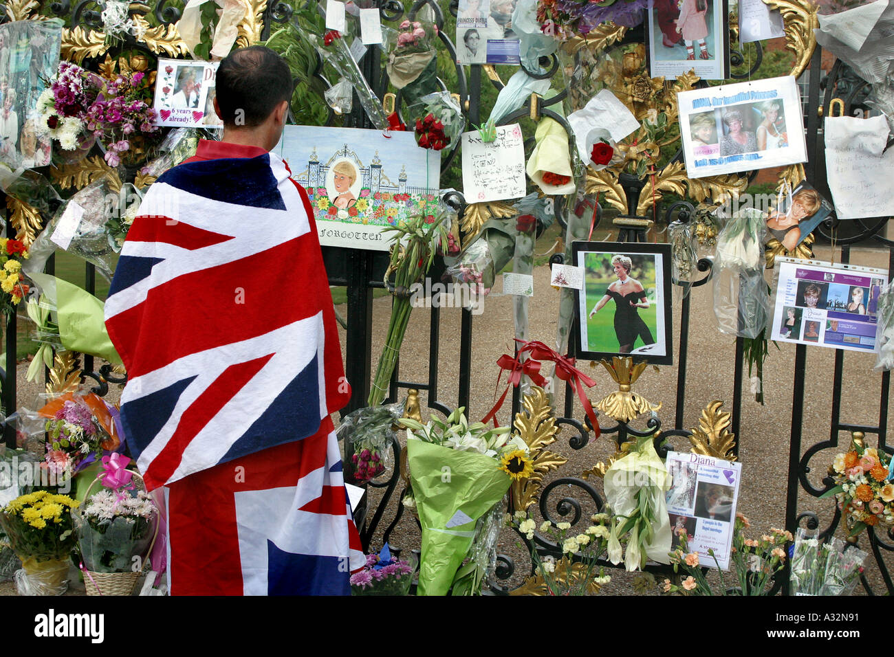 Mourner avvolto in unione jack guarda i messaggi appesi su Kensington palace cancelli in memoria della principessa Diana Foto Stock
