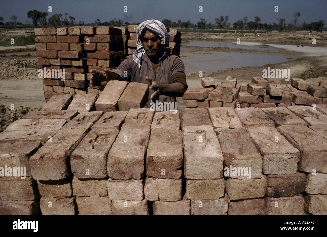Il lavoro coatto, un uomo di mattoni di impilamento in un forno di mattoni. Il Pakistan Foto Stock