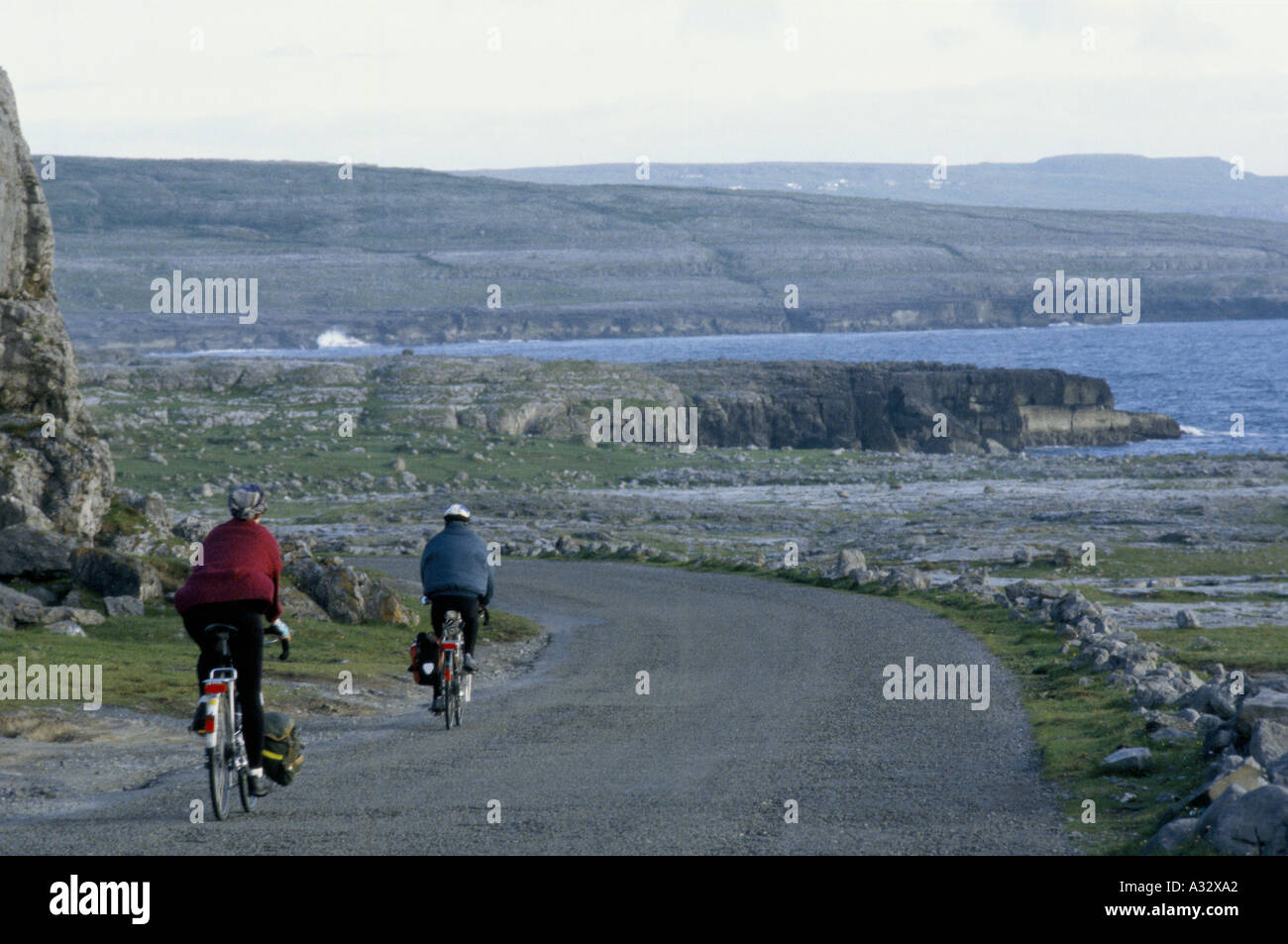 Giovane ciclismo su strada costiera nel Burren, County Clare, Irlanda Eire 1995 Foto Stock