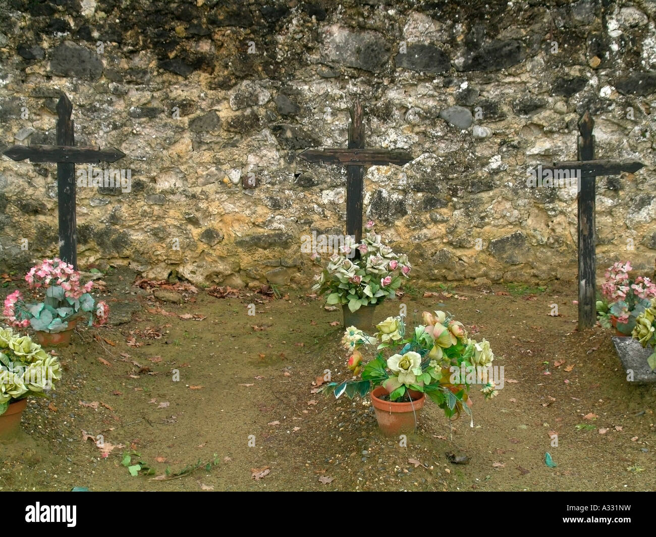 Tre in legno antico attraversa gravi sui poveri semplici tombe con fiori artificiali in un vecchio cimitero cimitero Foto Stock