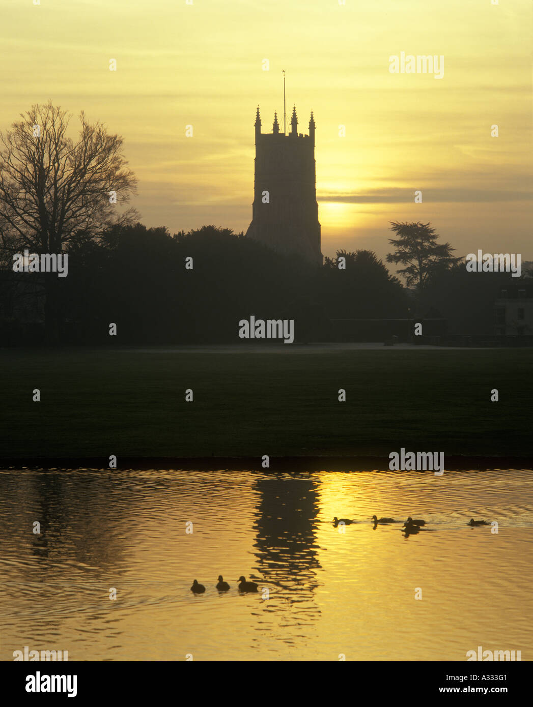 La chiesa di San Giovanni Battista, vista attraverso il lago Abbey Grounds, nella città Cotswold di Cirencester, Gloucestershire UK Foto Stock