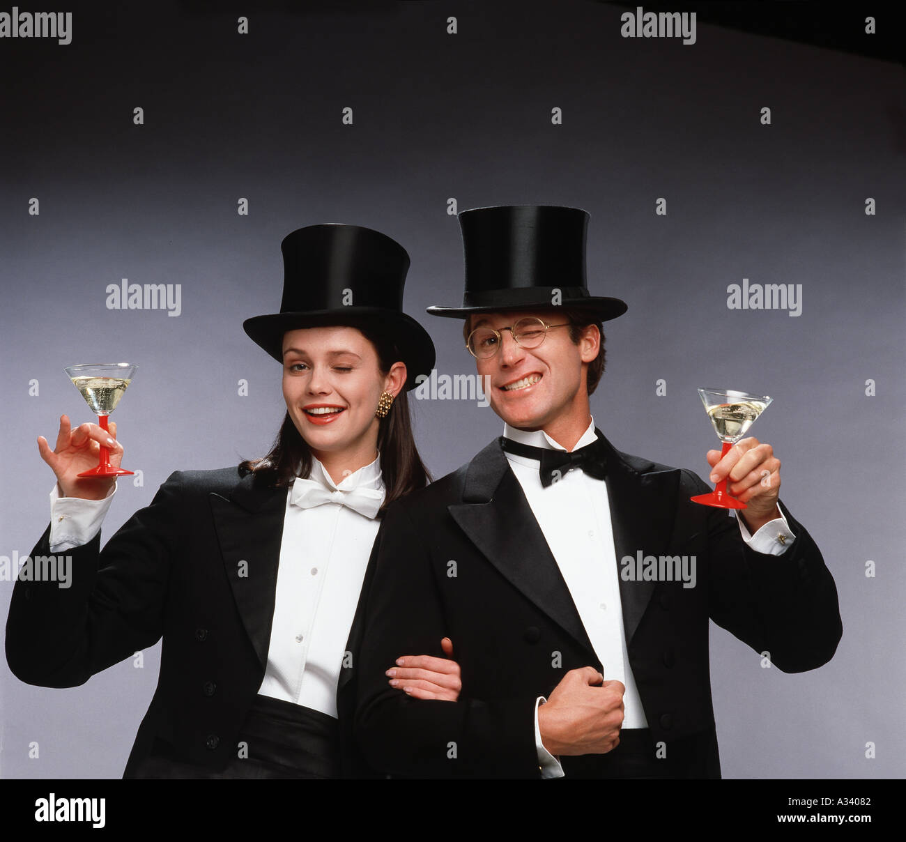 Coppia giovane vestito in tailcoats con wineglasses, divertendosi e mi congratulo con la telecamera. Foto Stock