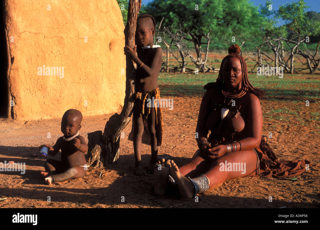 Himba tribù Ovahimba donna con bambini seduti davanti al rifugio Kraal interno Kaokoveld Namibia Africa Foto Stock