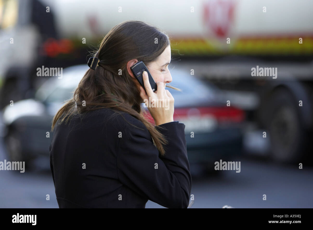 Lunghi capelli scuri ragazza irlandese con fermaglio per capelli indossando abito nero camicia su un telefono cellulare Nokia in parte anteriore del traffico in Dublino Foto Stock