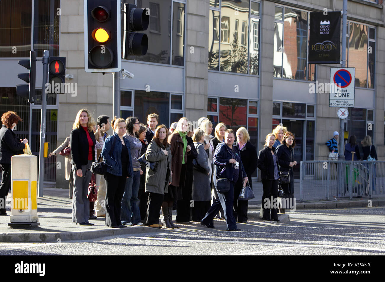 La folla di persone in attesa sul cambiamento di luce di attraversare la strada al semaforo in un centro della città Foto Stock