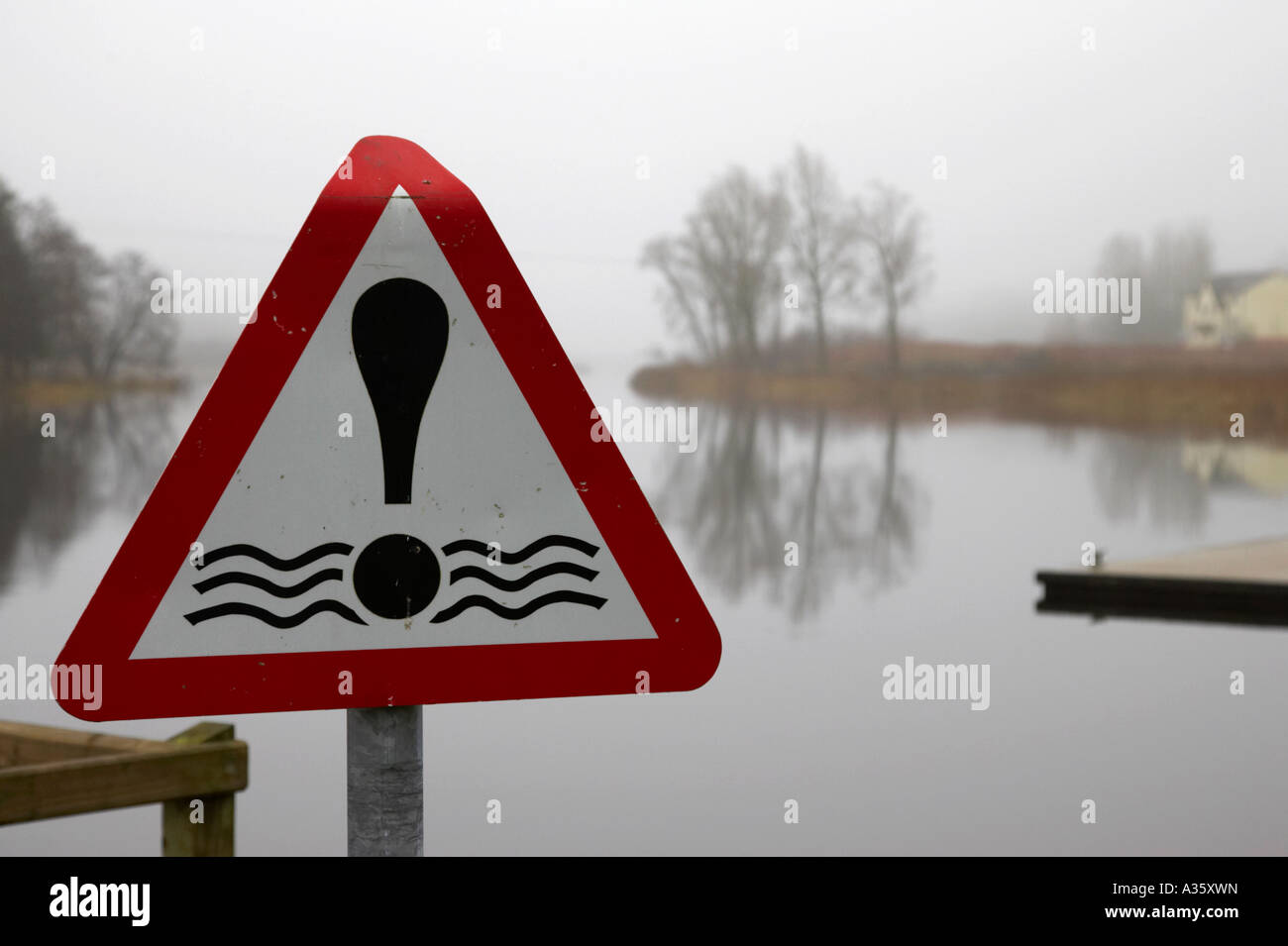 Red triangolare di pericolo acqua segno accanto al molo sul fiume Erne in Enniskillen in una nebbiosa giornata invernale Foto Stock