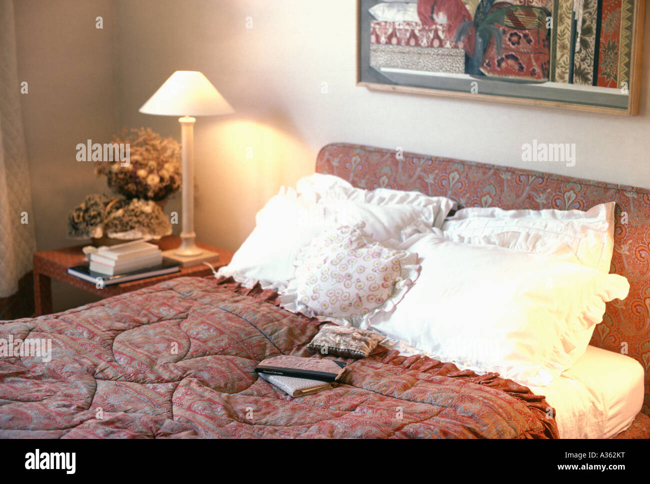 Camera da letto con cuscini di colore bianco e rosso modellato quilton bed e acceso la lampada sul comodino Foto Stock