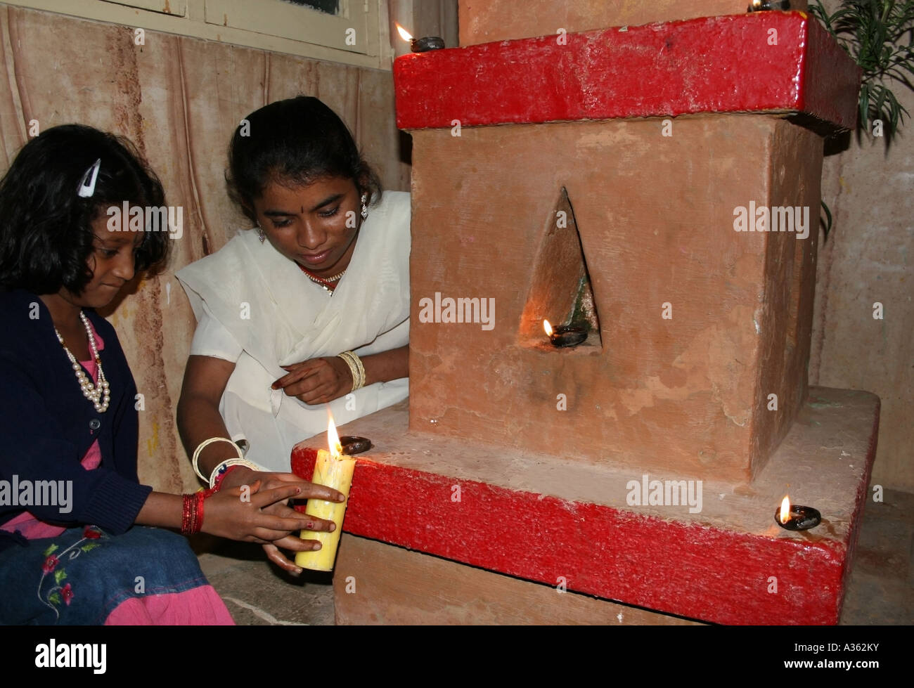 La madre aiuta il bambino luce dive di piccole dimensioni al di fuori della loro casa in India Foto Stock