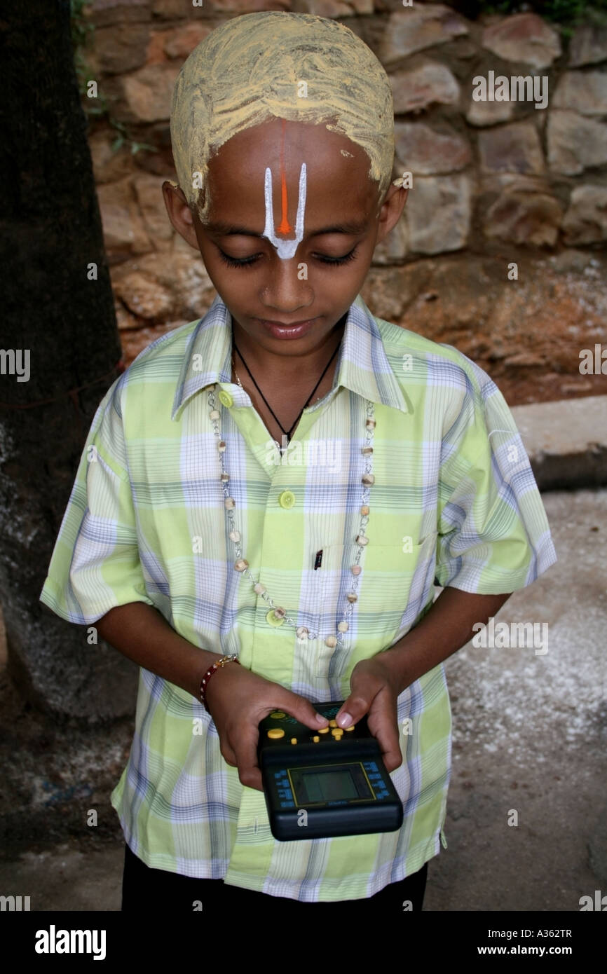 Giovane pellegrino gioca sulla sua playstation , Tirumala , India Foto Stock