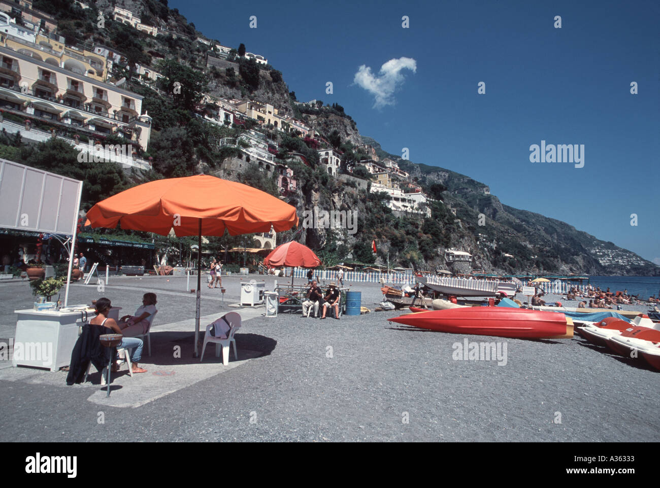 Spiaggia di Amalfi in scena con ombrello arancione e blu cielo con un filo di una nuvola Foto Stock
