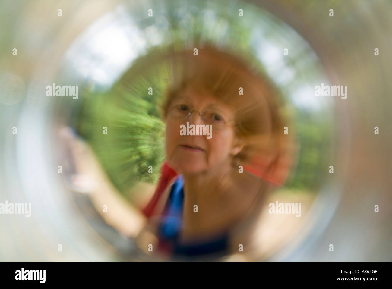 Donna matura osservata attraverso un fondo di un vetro Foto Stock