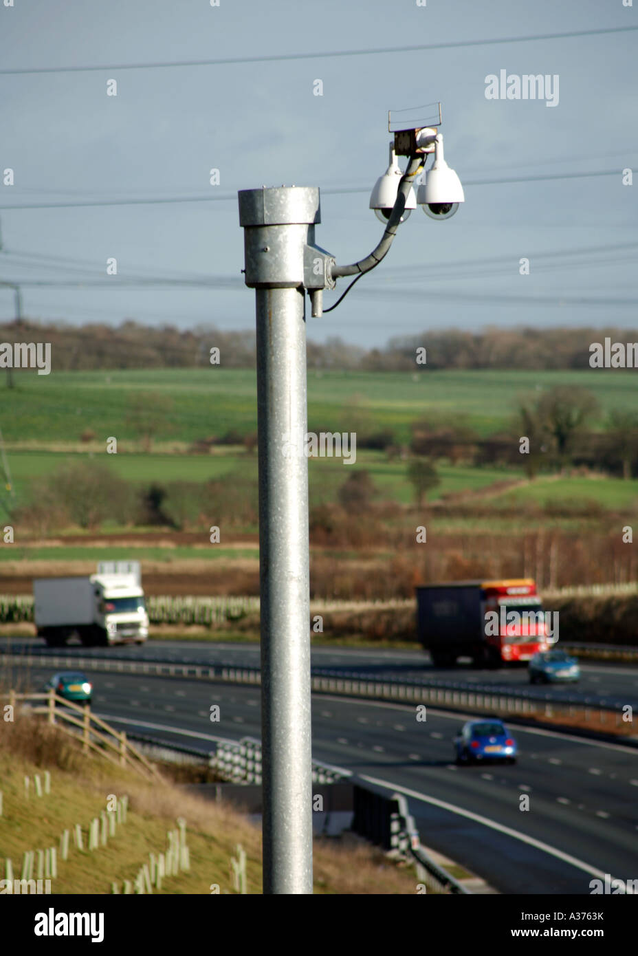 La vigilanza della polizia fotocamera accanto all'autostrada trafficata Inghilterra con il traffico velocizzando il passato Foto Stock