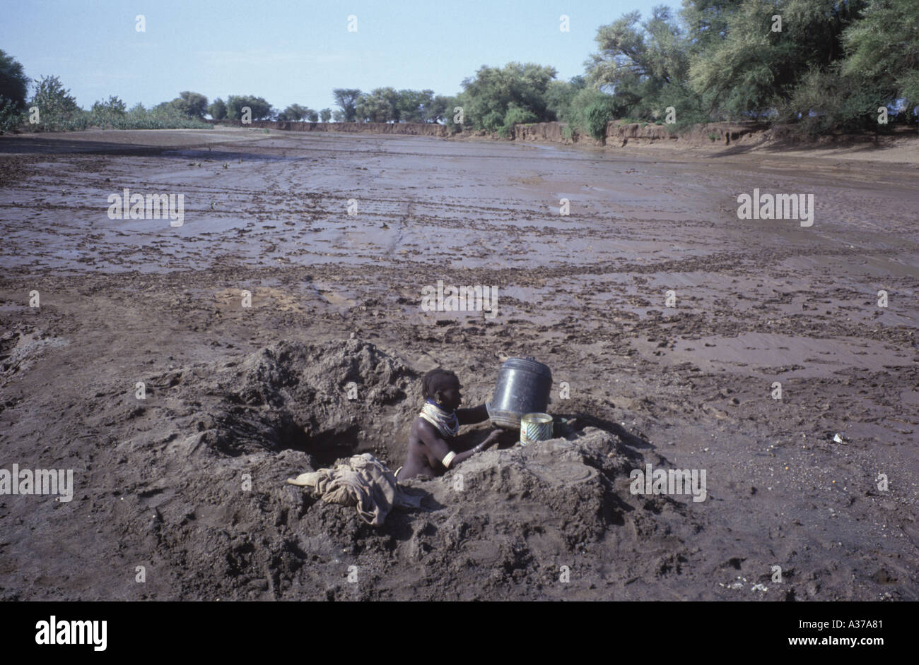 Una donna Turkana si raccoglie acqua da una vicina sorgente di messa a terra al suo villaggio nel nord del Kenya Foto Stock