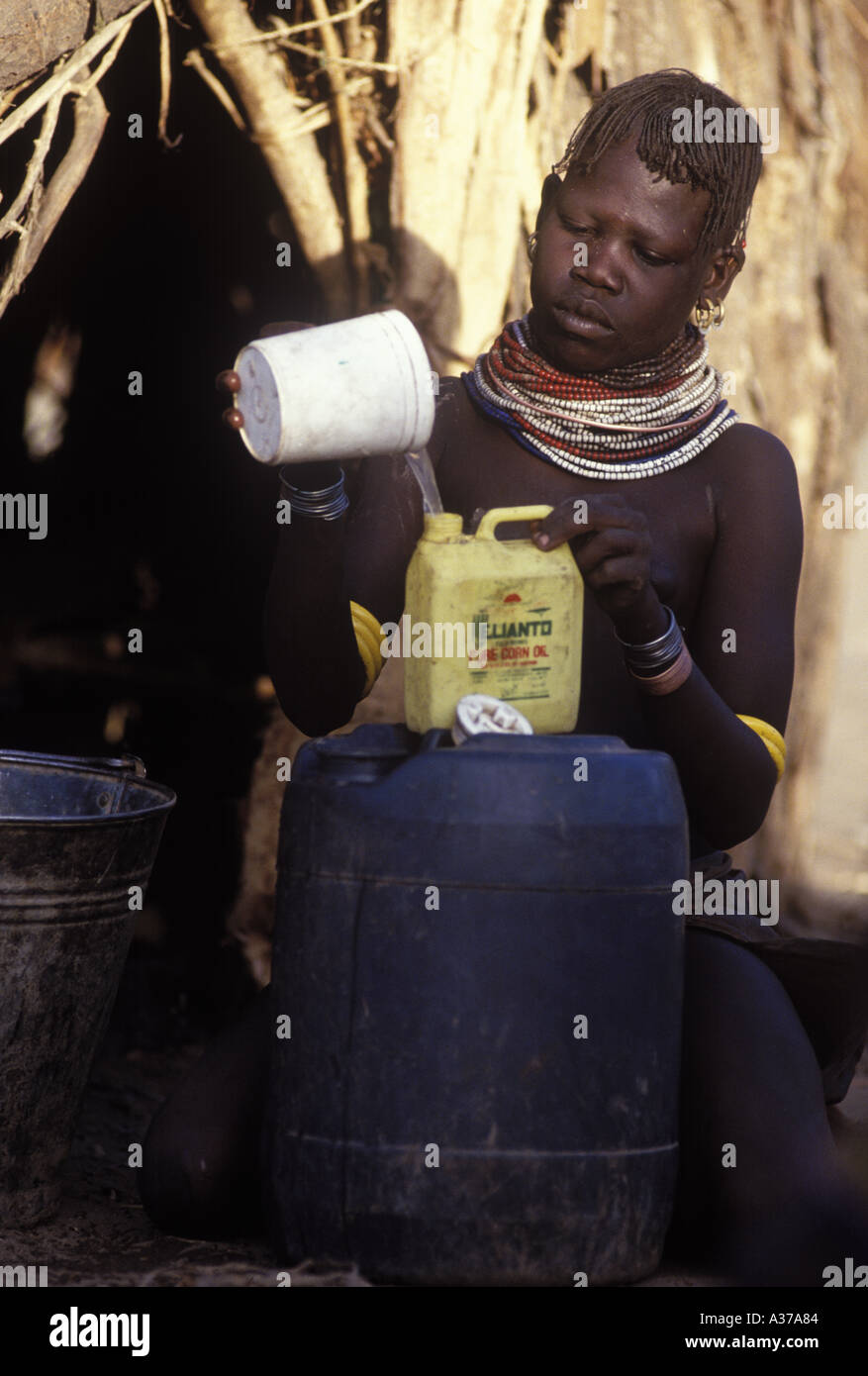 Una donna Turkana versando acqua di pozzo in più contenitori gestibile Kakuma in Kenya Foto Stock