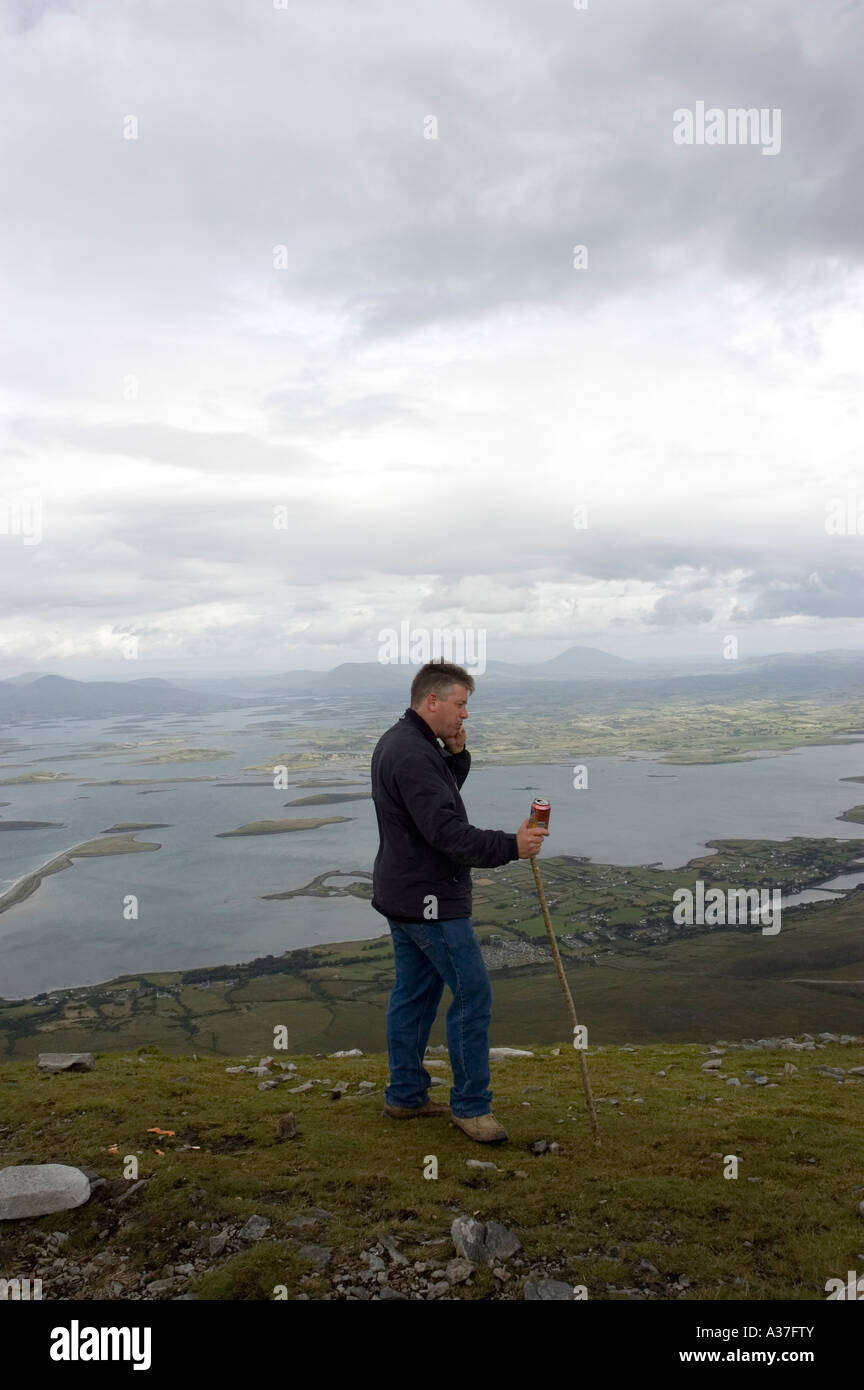 Un pellegrino su un telefono mobile sulla parte superiore di Croagh Patrick, County Mayo, Irlanda Foto Stock