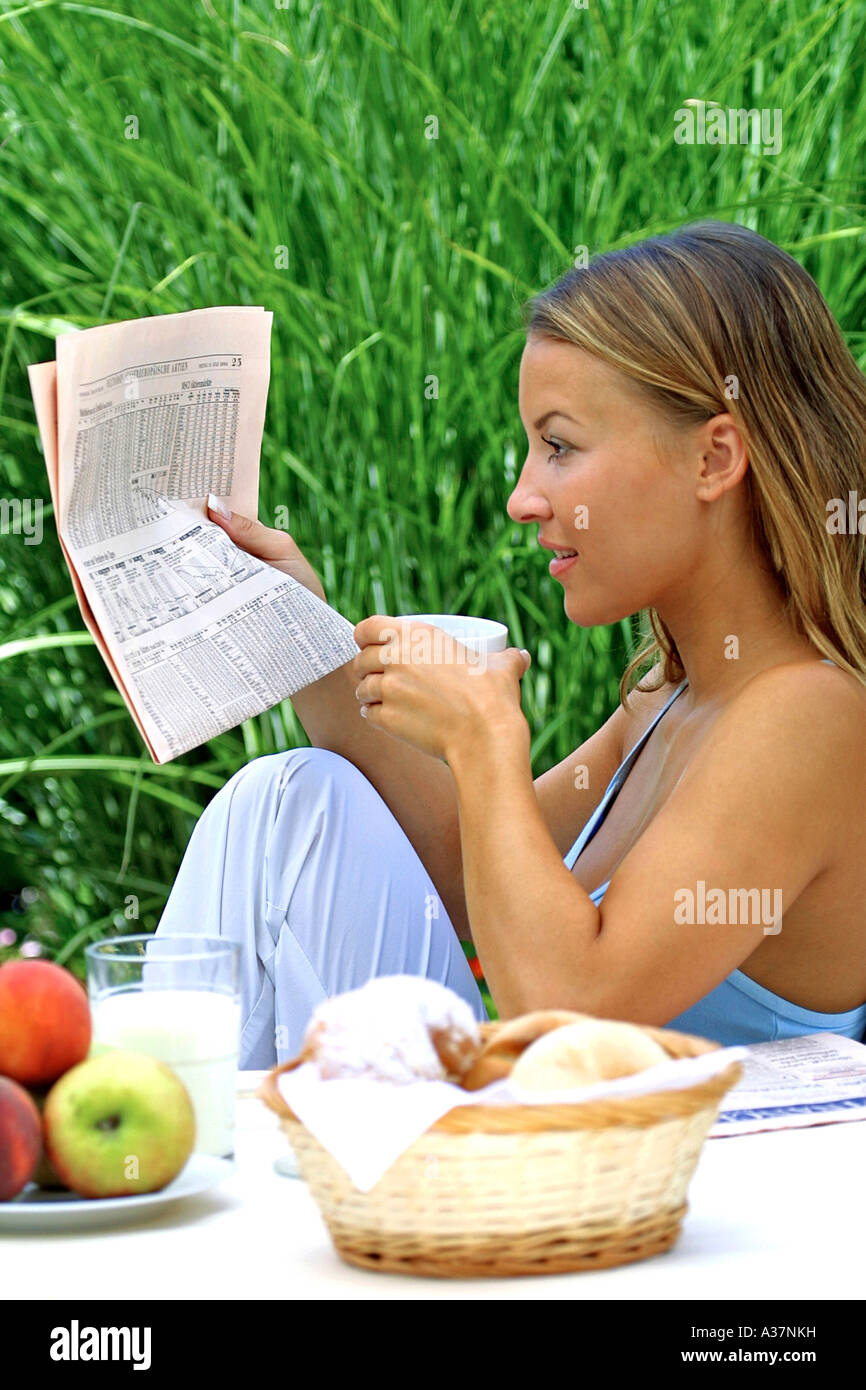 Frau fruehstueckt und liest Zeitung, donna con prima colazione e quotidiano di lettura Foto Stock