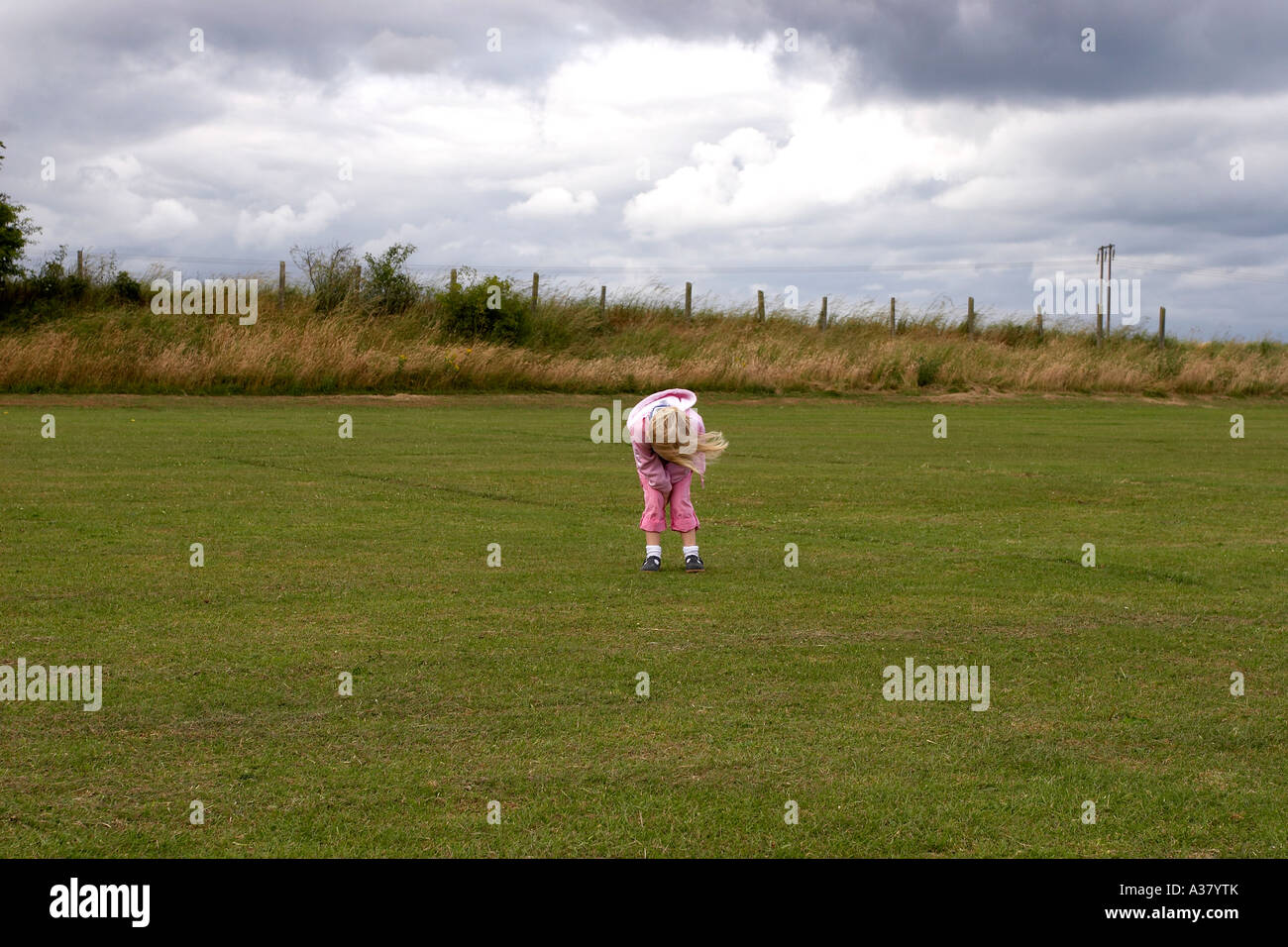 Bambina di piegarsi in un campo Foto Stock