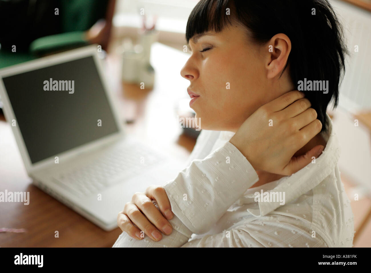 Donna con mal di spalla da utilizzando il computer Foto Stock