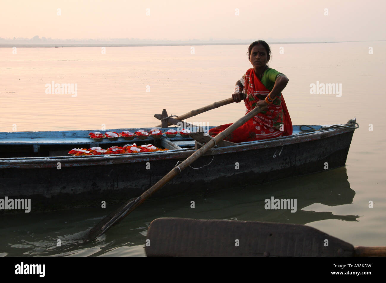 Donna vendita candela galleggiante e fiore offerte da la sua barca sul fiume santo Ganges, Varanasi, Uttar Pradesh, India Foto Stock