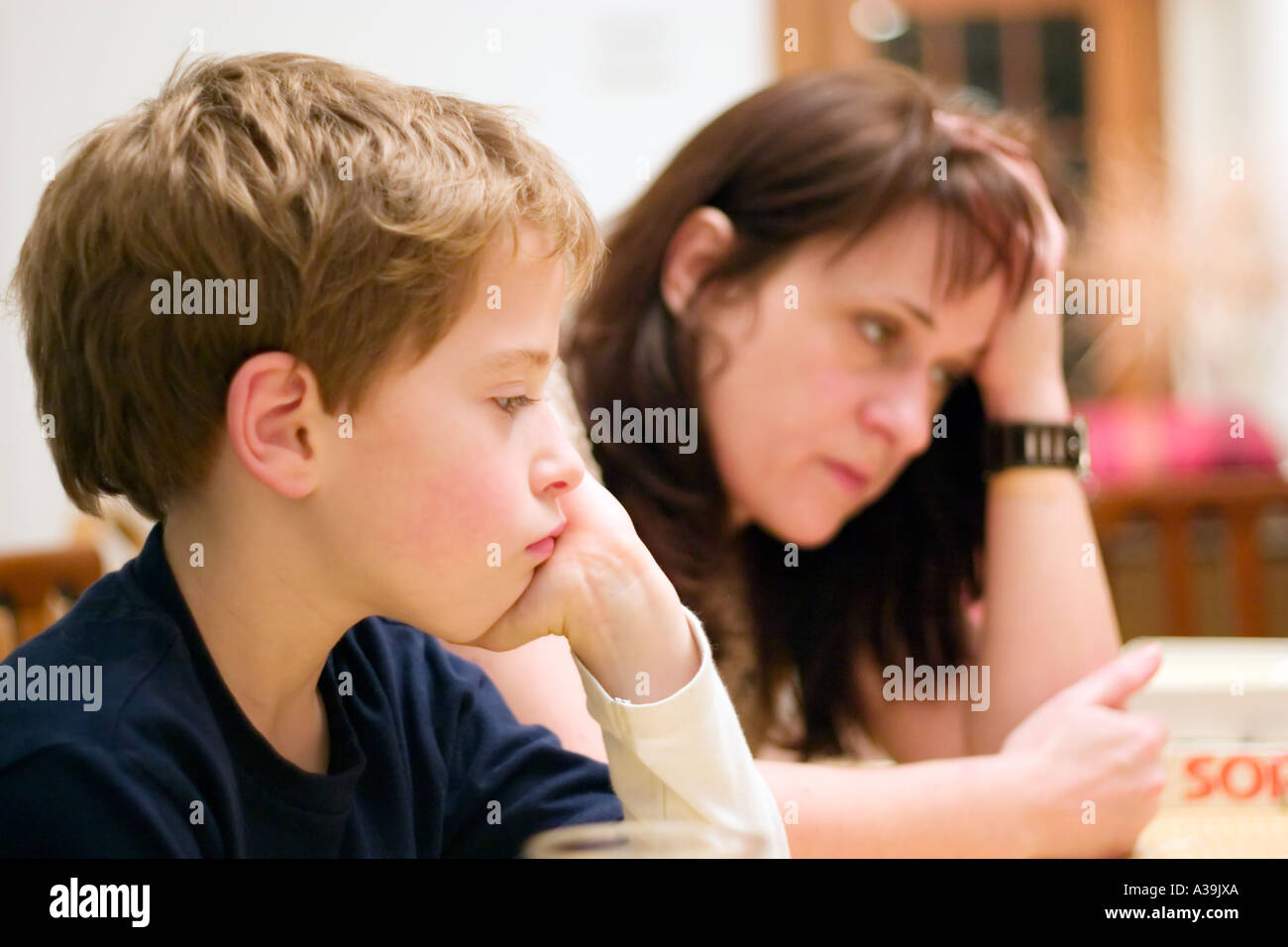 La madre e il bambino guardando annoiato durante la riproduzione di un gioco da tavolo Foto Stock