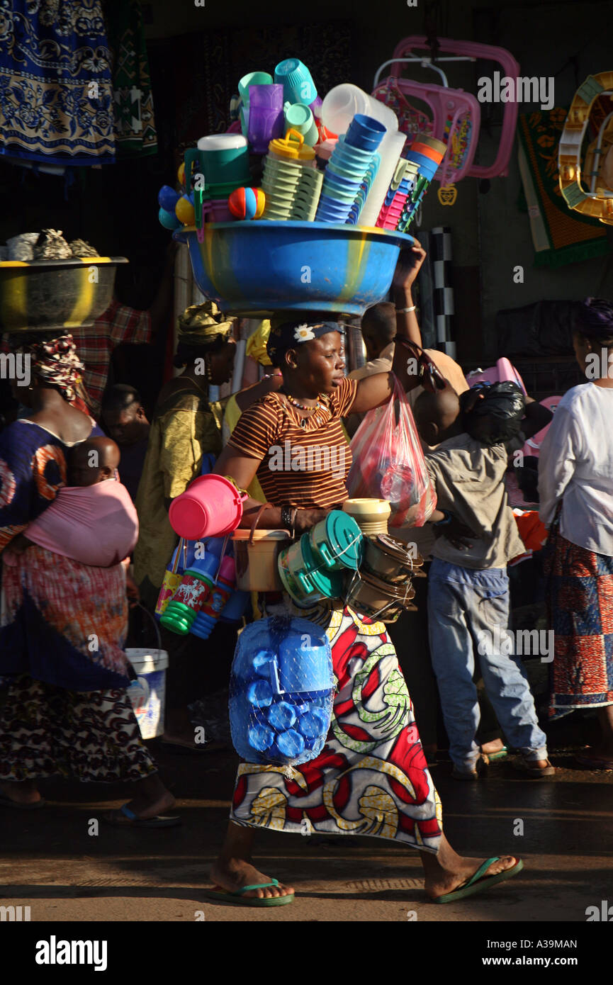 Una donna di vendere i prodotti in plastica passeggiate intorno al mercato cercando di vendere i suoi beni a Bamako nel Mali, Africa Foto Stock