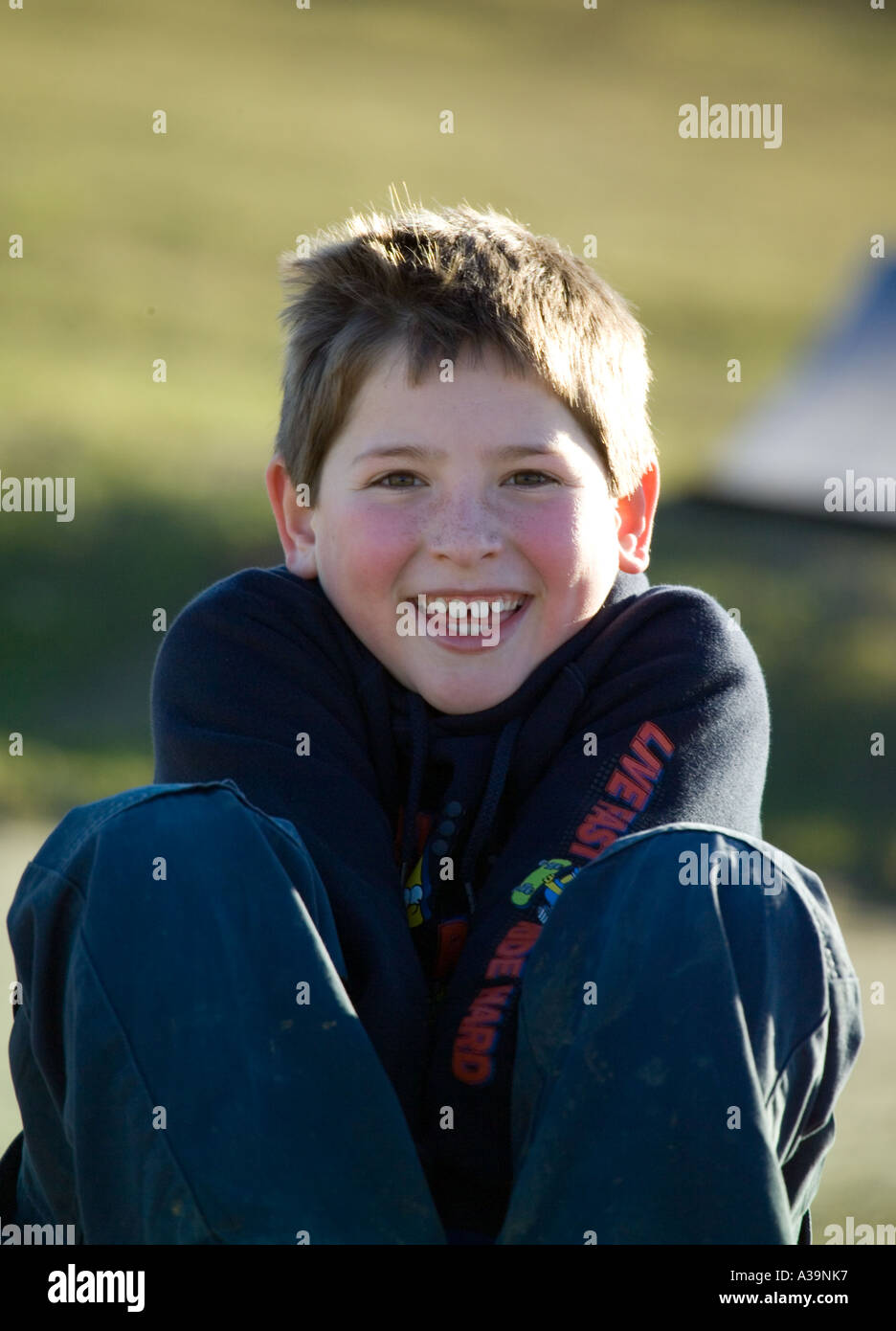 9 anni felici bianco ragazzo seduto su skateboard in inverno al di fuori Foto Stock
