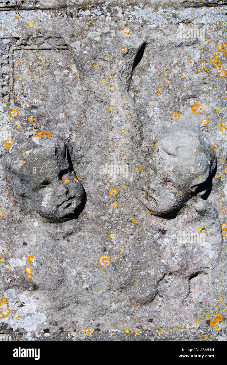 Cherubic faccia su una lastra tombale con lichene arancione, Painswick Chiesa Gloucestershire Foto Stock