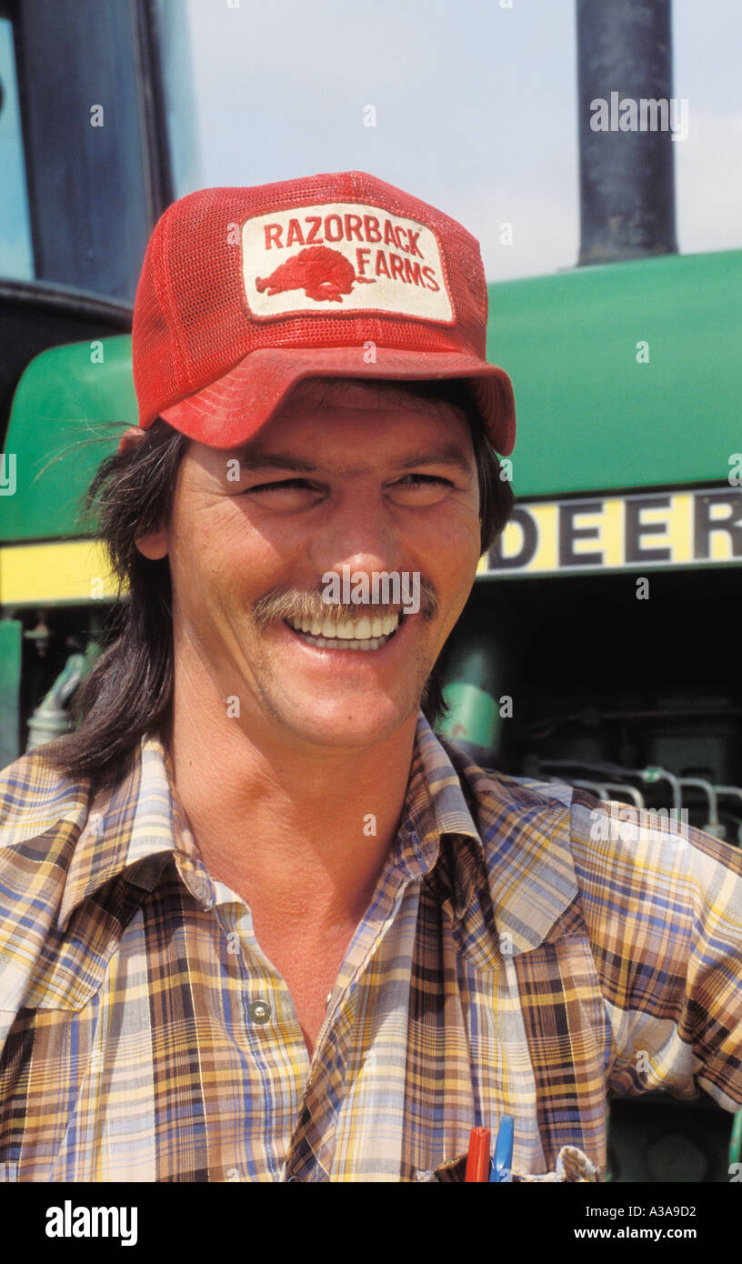Un sorridente giovane agricoltore con un baffi indossa un cappello rosso  nella parte anteriore di un verde trattore John Deere in una fattoria in  Arkansas modello rel Foto stock - Alamy