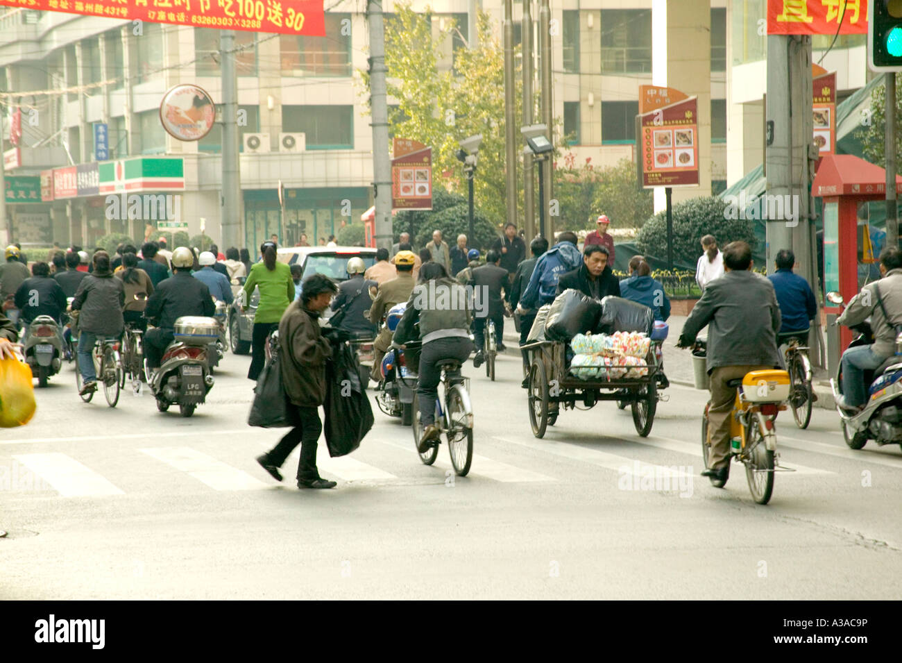 I piloti del ciclo e pedoni sulla strada di città, Shanghai, Cina Foto Stock